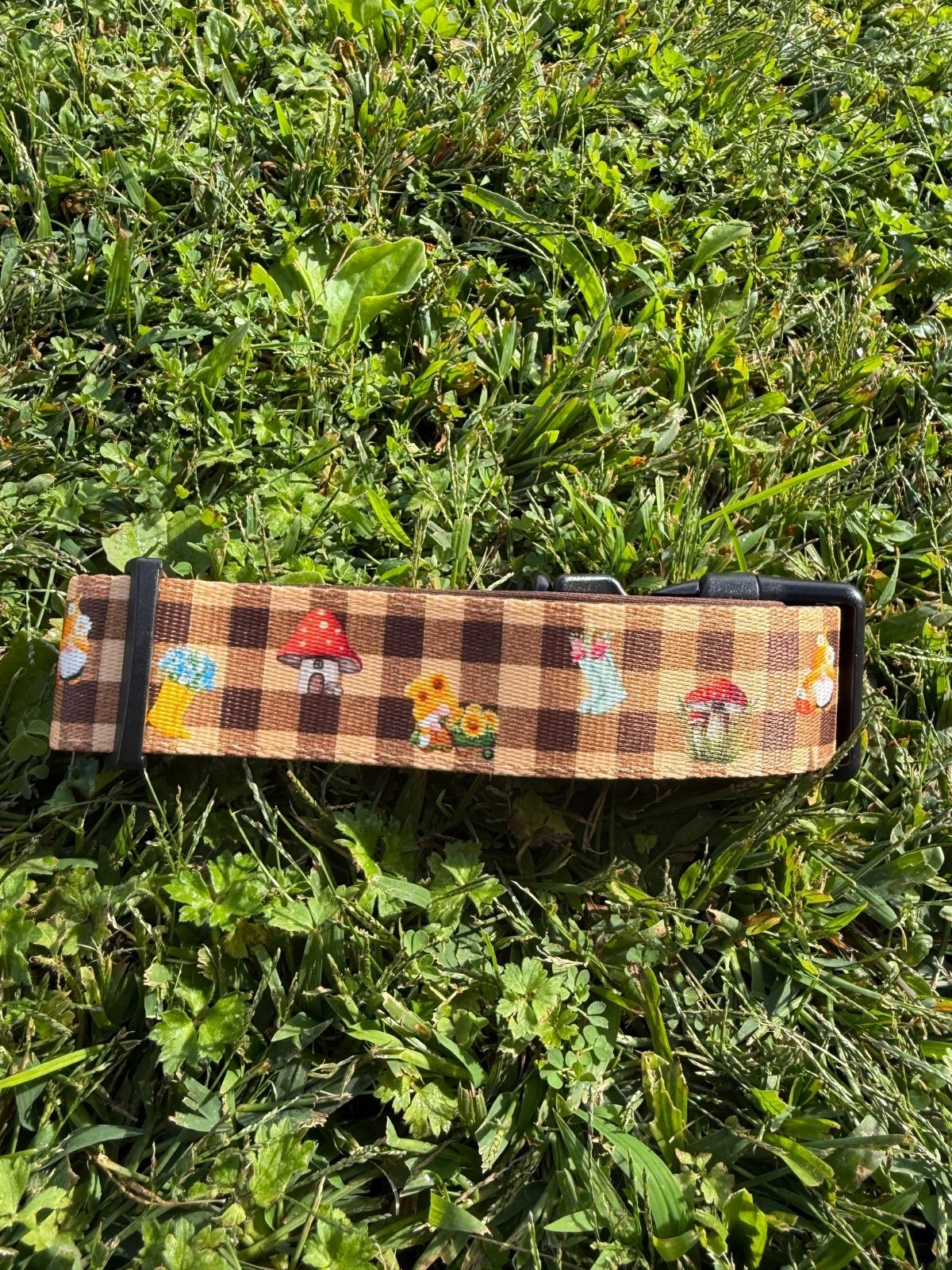 Detalle del estampado de duendes, setas y botas del collar todoterreno Trasno sobre la hierba