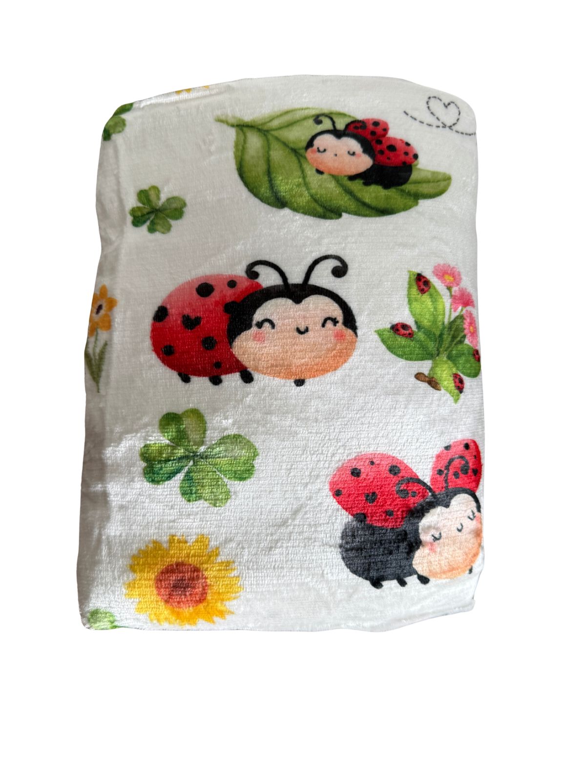 Manta de borreguillo Mariquiña doblada con mariquitas sonrientes, tréboles y girasol