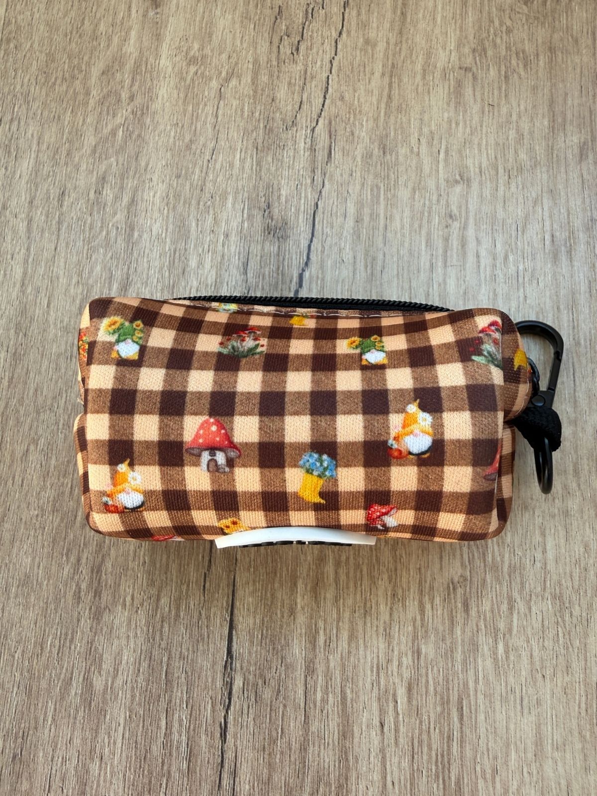 Porta bolsas Trasno con cremallera y estampado de duendes, setas y botas sobre mesa de madera